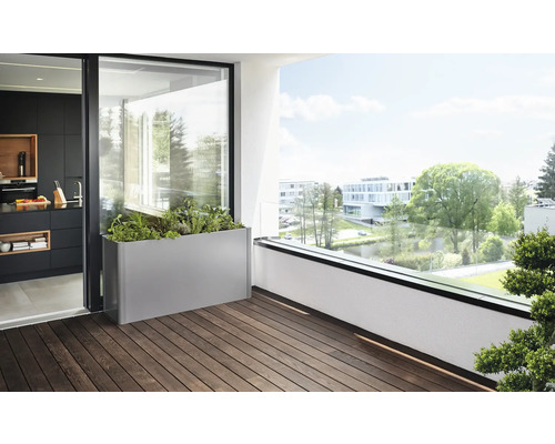 Scène de balcon avec un bac à fleurs en métal, planté d''herbes et de plantes, sur un plancher en bois