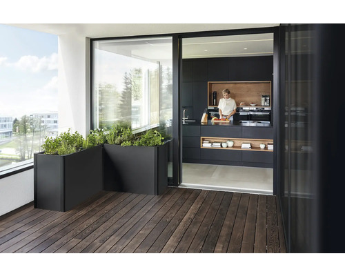 Balcon avec jardinières et cuisine ouverte avec une femme préparant des plats.