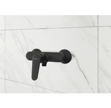 Mitigeur de douche noir sur un mur carrelé blanc