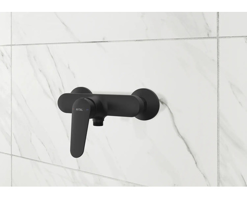 Mitigeur de douche noir sur un mur carrelé blanc