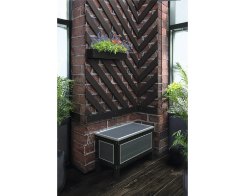 Coin avec un coffre, une jardinière et des lattes décoratives en bois sur un mur en briques