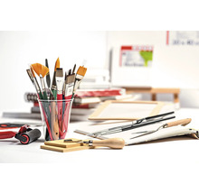 Espace de travail créatif avec des pinceaux, un rouleau de peinture et des outils sur une table.