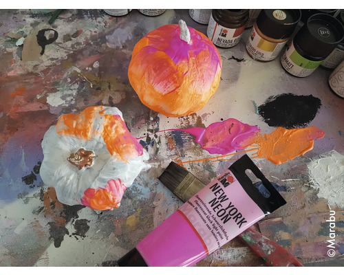 Citrouilles décoratives avec peinture, pinceau et tubes de peinture sur une table