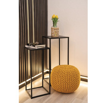 Zwei Beistelltische mit schwarzem Metallgestell, ein gelber Pouf und eine Vase mit gelben Tulpen