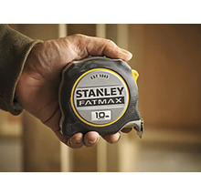 Mètre ruban Stanley Fatmax d''une longueur de 10 mètres tenu dans une main.