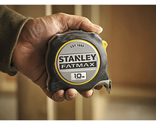 Mètre ruban Stanley Fatmax d''une longueur de 10 mètres tenu dans une main.