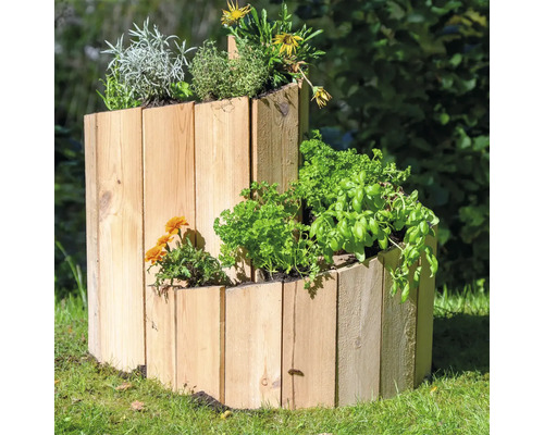 Kräuterspirale aus Holz mit verschiedenen Kräutern im Garten