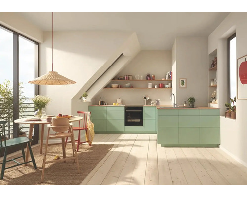 Helle Küche mit Essbereich, ausgestattet mit grünen Küchenschränken, Holztisch und Stühlen.
