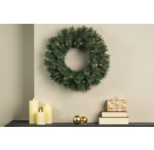 Scène de Noël avec couronne de sapin illuminée, bougies et cadeau