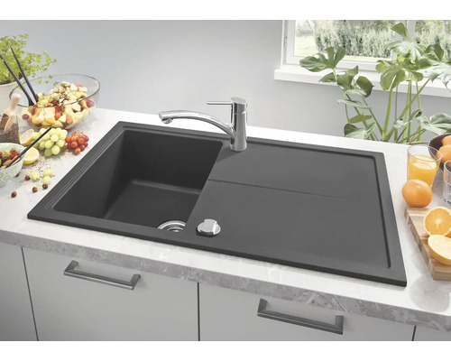 Dunkelgraue Küchenspüle mit Abtropffläche und Armatur auf einer Küchentheke