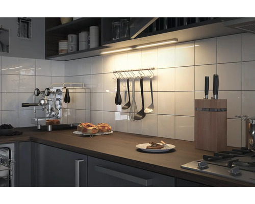 Scène de cuisine avec plan de travail, ustensiles de cuisine et luminaire sous meuble