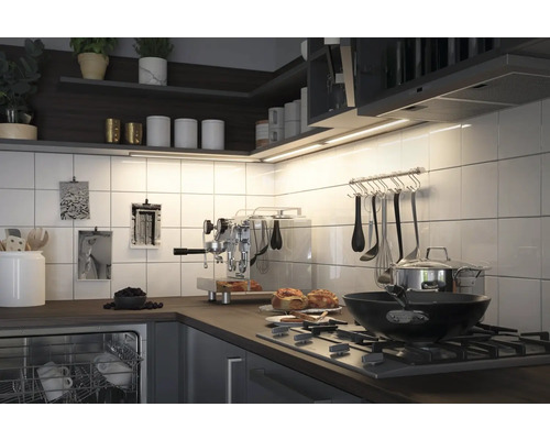 Cuisine claire avec carrelage, étagères, plaque de cuisson, vaisselle et objets de décoration