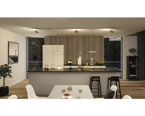 Cuisine moderne avec îlot central, table à manger et éclairage sur rail flexible.