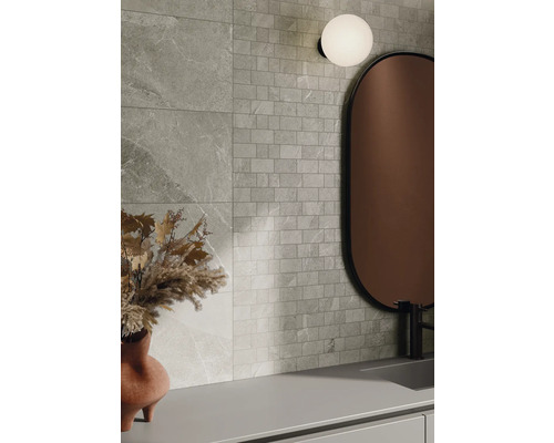 Aménagement mural avec des carreaux aspect pierre et des carreaux de mosaïque, combinés avec un miroir et une lampe