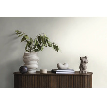 Dekoratives Interieur mit Vase, Büchern und Skulpturen auf einem Holzschrank