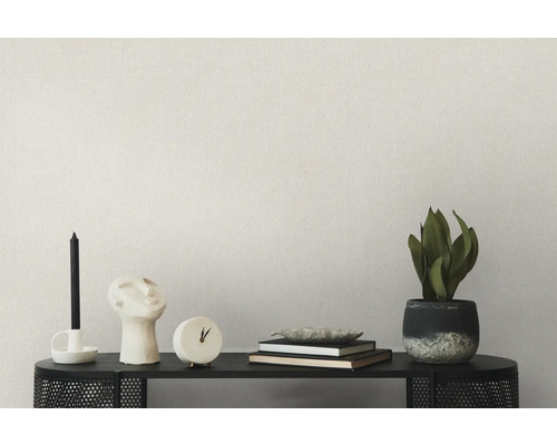 Décoration de salon sur une étagère avec bougies, sculpture, horloge, livres, bol et plante en pot devant un mur uni