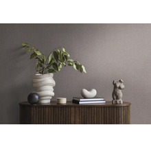 Dekoratives Arrangement auf einem Holzschrank mit Vase, Büchern und Skulptur
