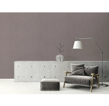 Wohnzimmer mit Sessel, Lampe und Dekorationsartikel auf Kommode vor gemusterter Wand