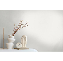 Arrangement décoratif avec vase, plantes, bougie, horloge et sculpture sur une table