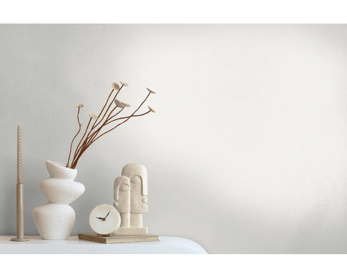 Arrangement décoratif avec vase, plantes, bougie, horloge et sculpture sur une table