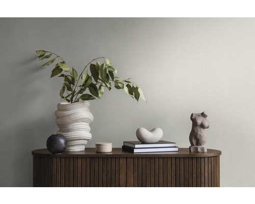 Dekoratives Interieur mit einer Vase, Büchern und Skulpturen auf einem Holzschrank.
