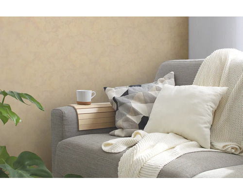 Canapé gris avec coussins, plaid, tablette d''accoudoir et tasse dans une pièce à vivre.