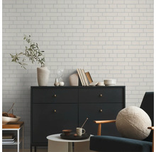 Espace de vie avec un mur à l''aspect brique, une commode et un fauteuil