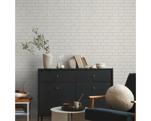 Wohnraum mit einer Wand in Backsteinoptik, einer Kommode und einem Sessel