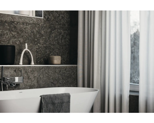 Badezimmer mit Badewanne, Fliesenwand, Vorhang und dekorativen Elementen.