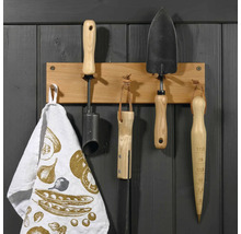 Outils de jardin suspendus à une barre en bois avec un torchon.