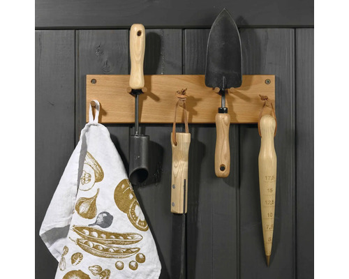 Outils de jardin suspendus à une barre en bois avec un torchon.