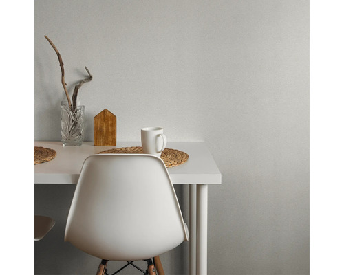 Szene mit weissem Tisch, Stuhl, Tasse, Holzdekoration und Glasvase.