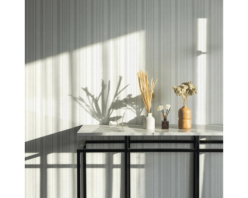 Fleurs séchées décoratives dans des vases sur une table devant un mur rayé.