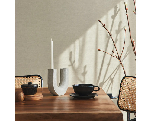 Décoration de table à manger avec bougeoir, bol, tasse et branches devant un mur texturé