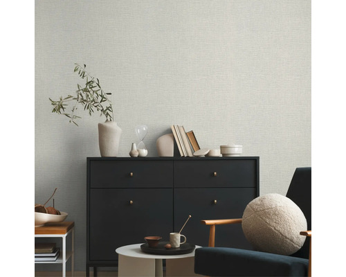 Wohnzimmer mit Textiltapete, Kommode und Sessel.