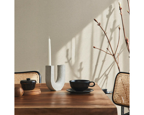 Scène de table à manger avec bougeoir, vaisselle et branches devant un mur clair