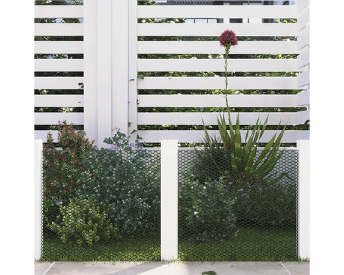 Filet de confidentialité devant des plantes et une clôture blanche