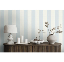 Pièce décorative avec papier peint à rayures, lampe de table, bougies, bol et vase sur une armoire