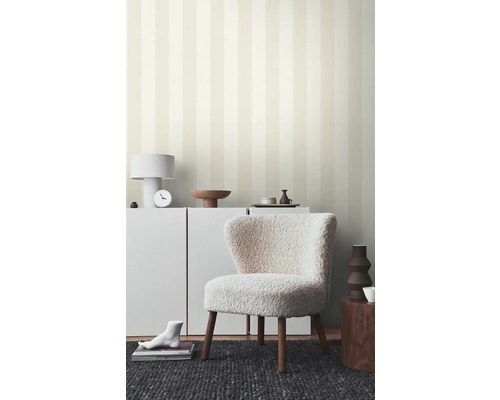 Wohnraum mit gestreifter Tapete, Sessel und weißen Möbeln für eine helle Atmosphäre