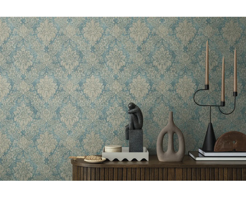 Intérieur décoratif avec papier peint à motifs, sculpture, chandelier et éléments décoratifs sur une armoire en bois.