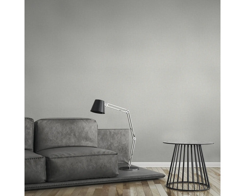 Wohnzimmer mit grauer Couch, Stehlampe und Beistelltisch vor einer Wandtapete.