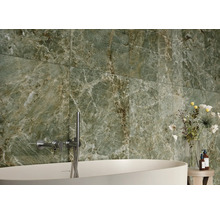 Salle de bain avec carrelage en marbre vert, baignoire et robinetterie.