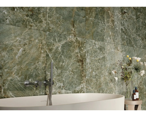 Salle de bain avec carrelage en marbre vert, baignoire et robinetterie.