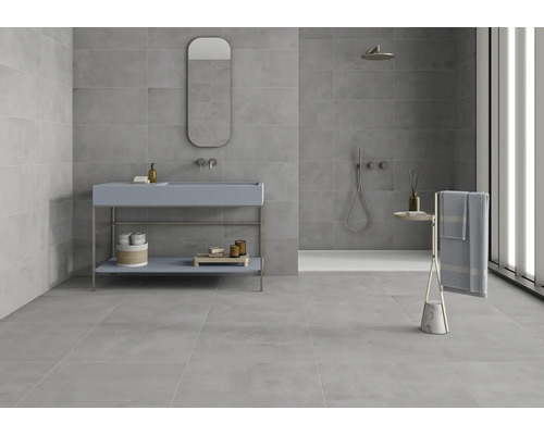 Salle de bains moderne avec carrelage gris, lavabo, miroir et porte-serviettes.