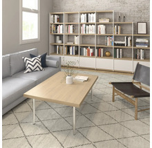 Salon avec bibliothèque, canapé, table basse et fauteuil sur un tapis