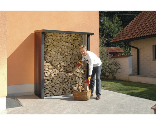 Person befüllt Holzkorb an einem Holzregal