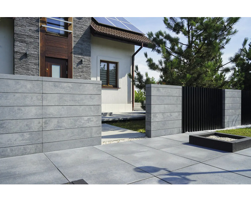 Aussenansicht eines Hauses mit Betonzaun und Steinplattenweg