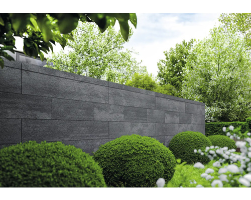 Gartenansicht mit Mauer aus Steinpaneelen und grünen Büschen