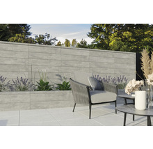 Aménagement de jardin avec mur en pierre grise, parterre planté et coin salon