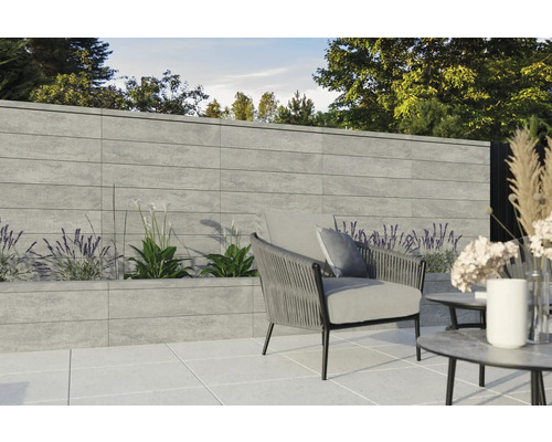 Terrasse avec mur en béton, parterre de plantes, fauteuil et table